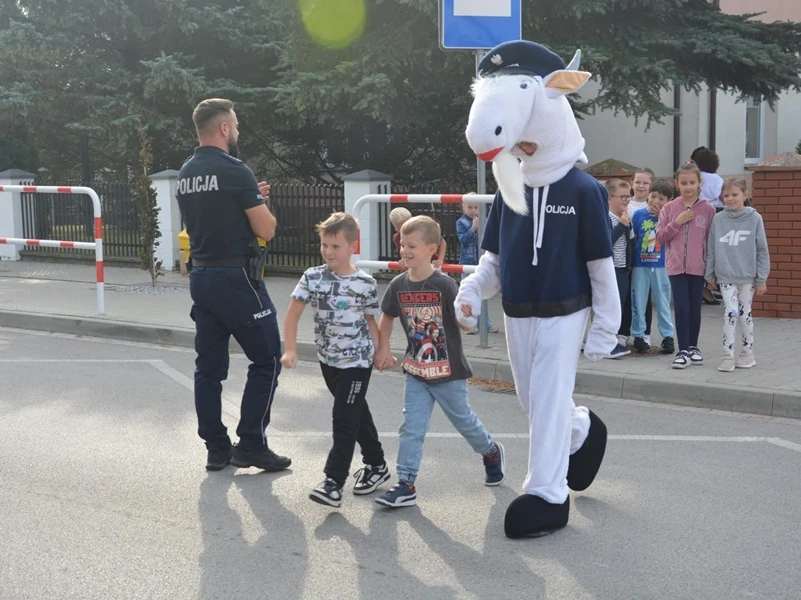 Koziołek z policjantem przeprowadzają uczniów przez ulicę