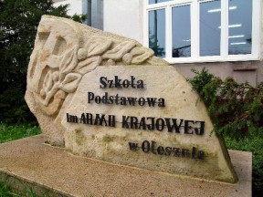 Kamień z napisem: Szkoła odstawowa im. Armii Krajowej w Olesznie
